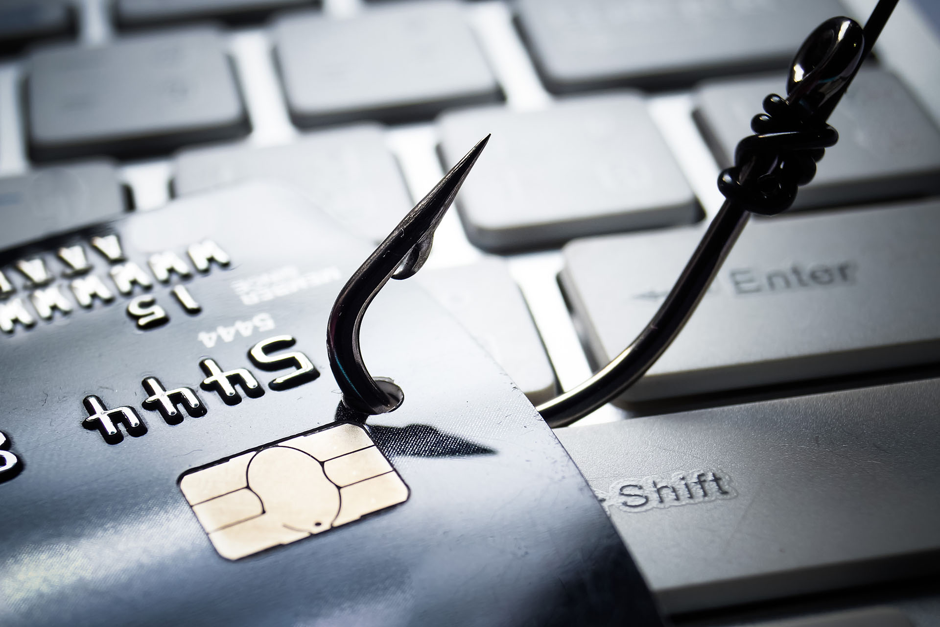 Fishing hook resting on a computer keyboard, representing a phishing attack